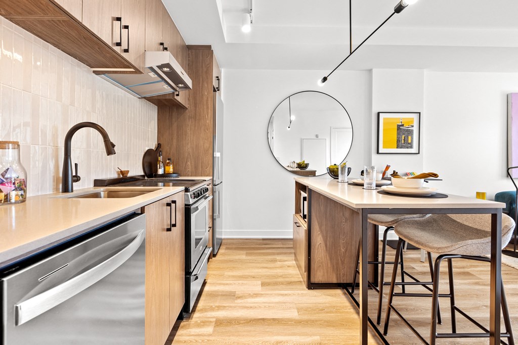a kitchen with an island with stools and a sink and a mirror