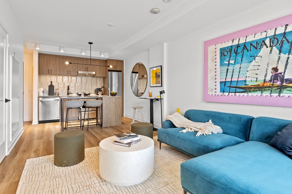 a living room with a blue couch and a kitchen in the background