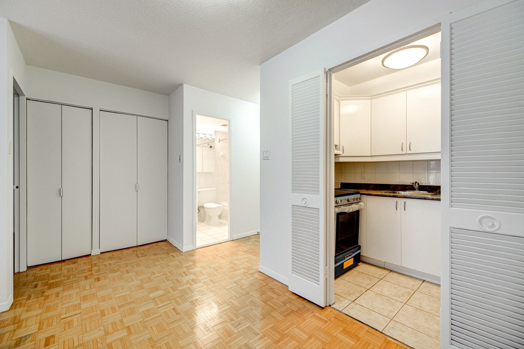 a renovated living room and kitchen with white cabinets and a door to the bathroom