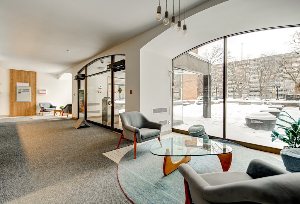 A modern lobby with a glass table and grey couches.