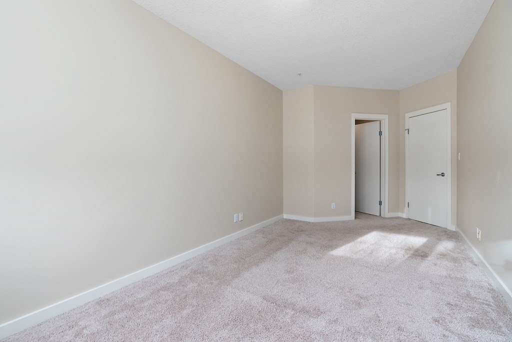 A room with a carpeted floor and two doors.