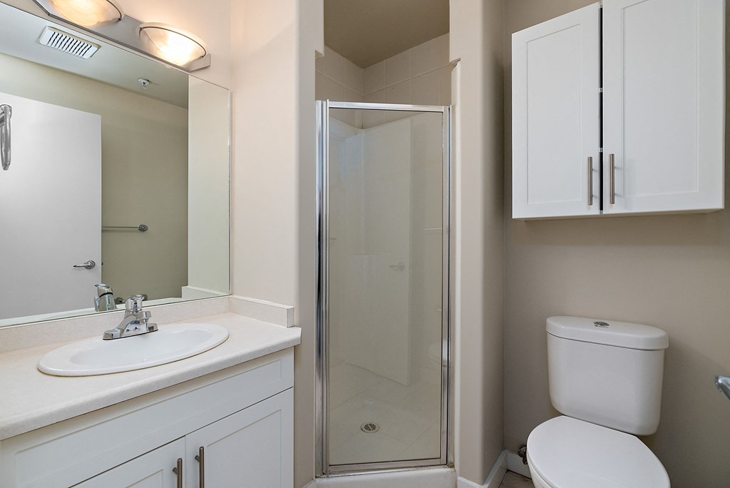 A white bathroom with a toilet, sink, and shower.