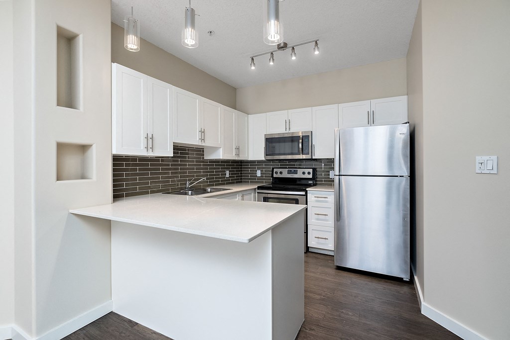 A kitchen with a white counter top and stainless steel appliances.