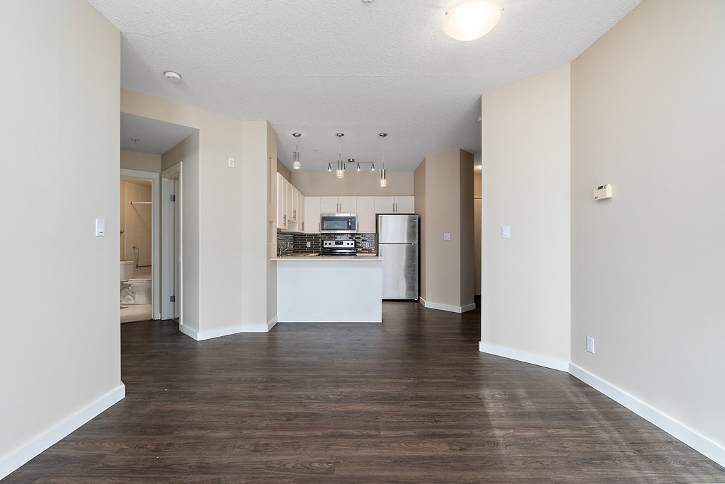A kitchen area with a refrigerator, sink, and cabinets.