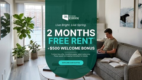 A man is sitting on a couch in a living room with a sign offering a free rent for 2 months and a $500 welcome bonus.