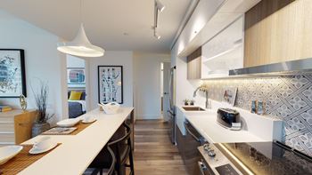 A modern kitchen with a long white island and a dining table with chairs.