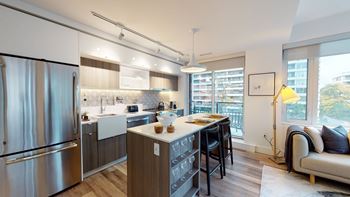 A modern kitchen with a refrigerator, sink, and dining table.