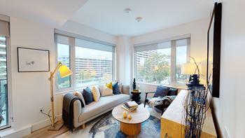 A living room with a grey couch, a yellow floor lamp, and a coffee table.