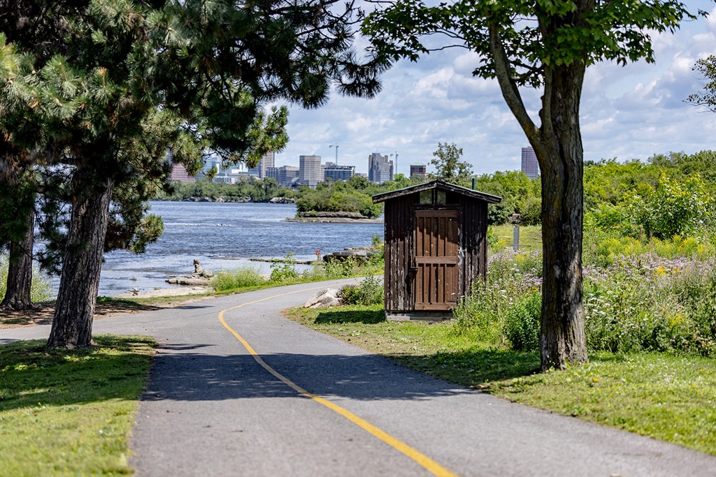 a path leading to a wooden outhouse next to a river