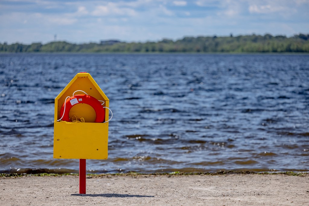 a yellow emergency box on the beach next to the water
