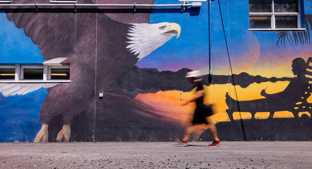 a person walking by a wall with a large eagle on it