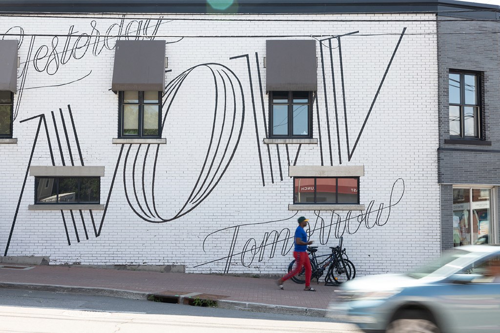 a man walks past a mural on the side of a building