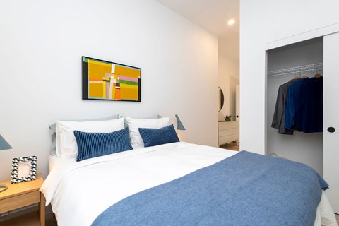A bedroom with a white bed and a blue blanket.