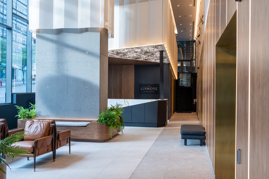 A modern waiting area with a large stone pillar and wooden furniture.