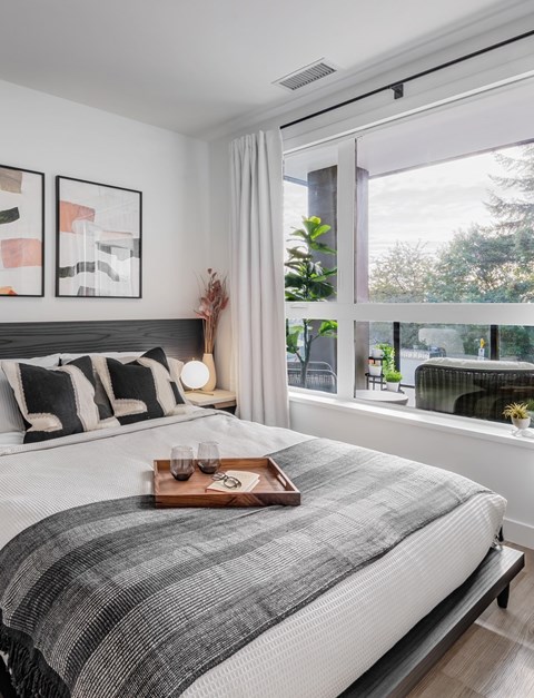 A bedroom with a large bed and a tray with glasses and a pair of sunglasses on it.
