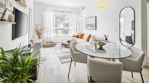 A modern dining room with a glass table and grey chairs.