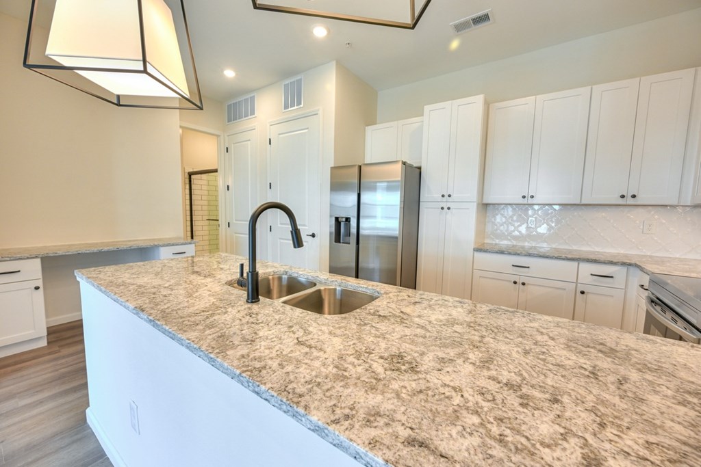 A kitchen with granite countertops and white cabinets.