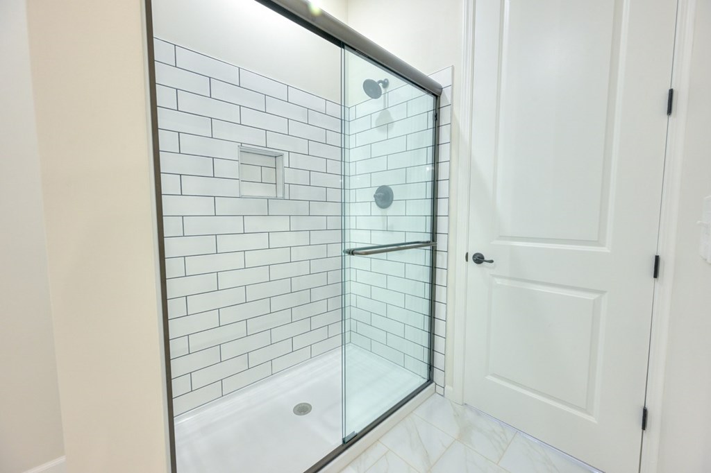A white door is next to a glass shower stall.