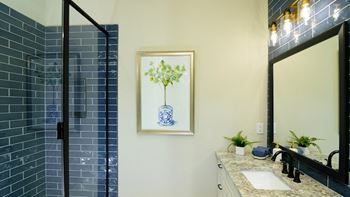a bathroom with a blue tiled shower and a blue and white vase of flowers on at Fairfax, Grandview, Ohio