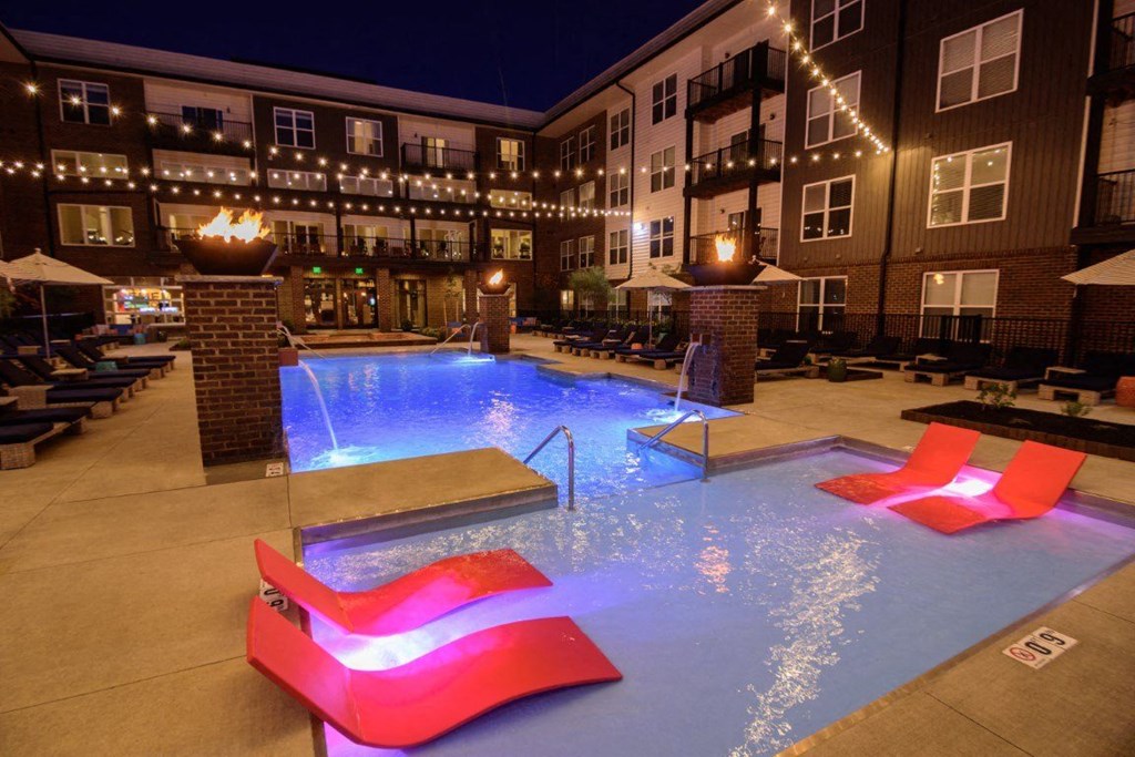 A pool with a red lighted bench in front of it.