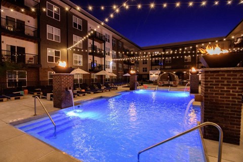 Illuminated courtyard pool with fire features at dusk at Madison Park Apartments, Columbus, Ohio