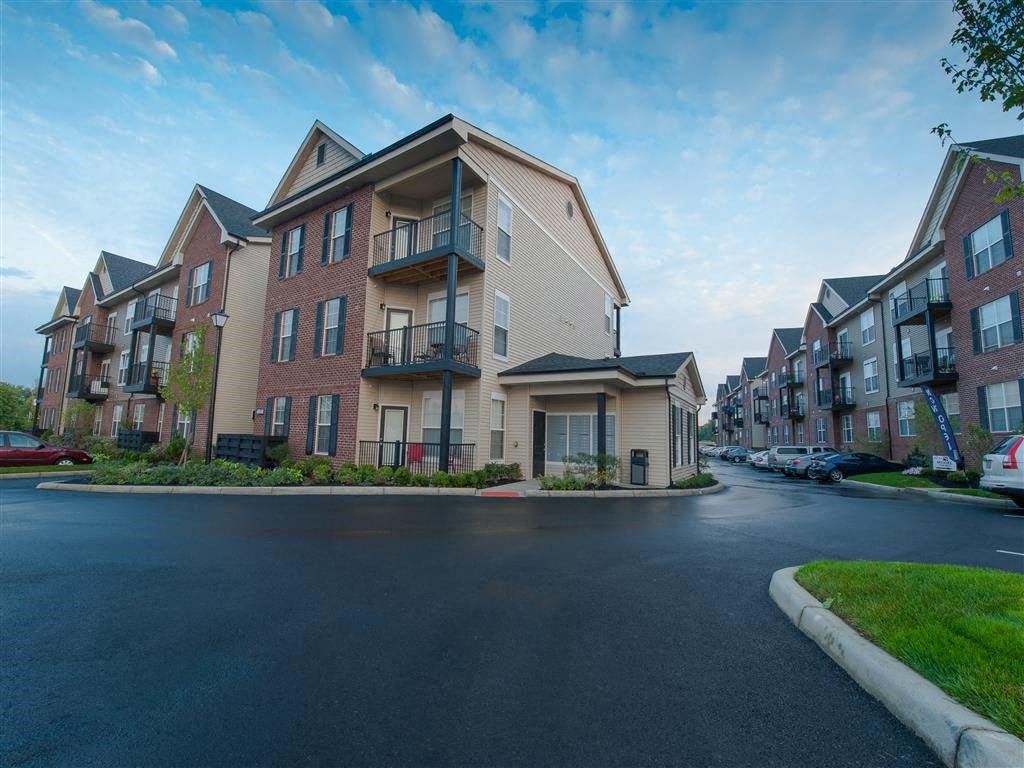 A row of apartment buildings with a car parked in front of the first one.