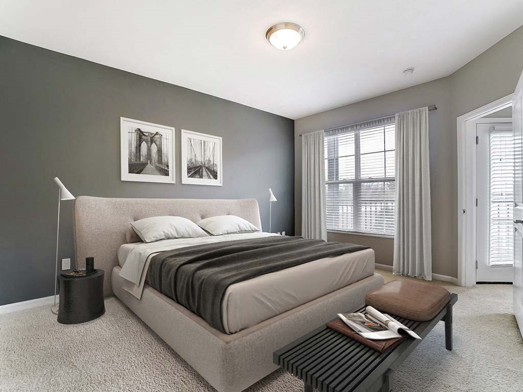 A bedroom with a large bed and a nightstand with a lamp.