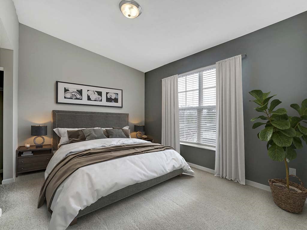 A bedroom with a large bed and a potted plant.