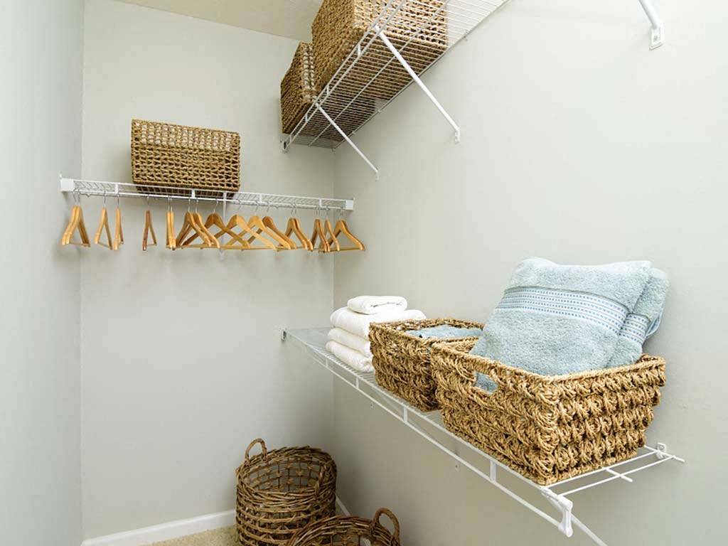 A white shelf with baskets and towels on it.