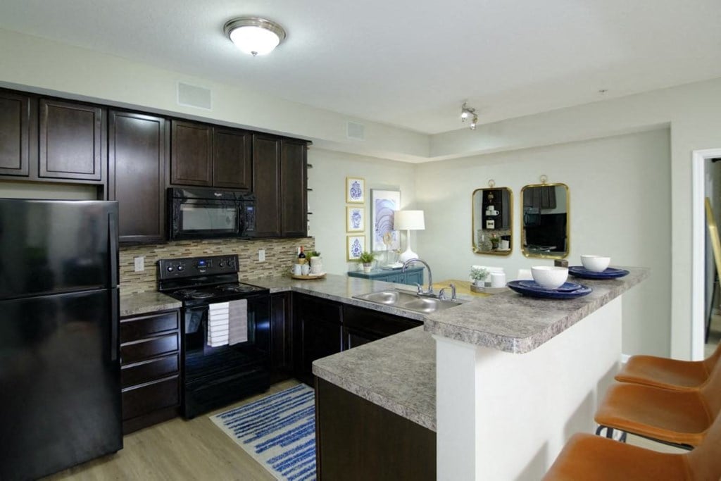 A kitchen with a black refrigerator and a black microwave.