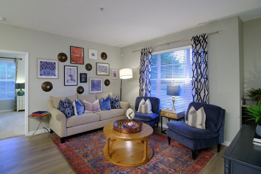 A living room with a couch, two chairs, a coffee table, and pictures on the wall.