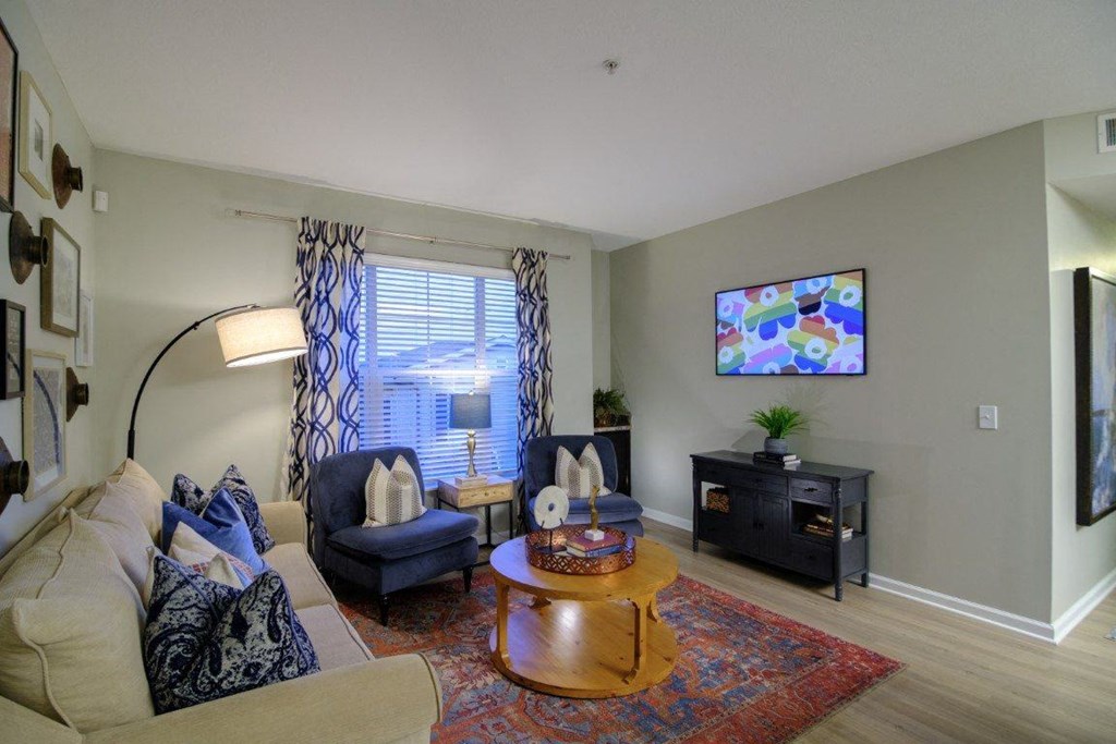 A living room with a couch, chair, and a television mounted on the wall.