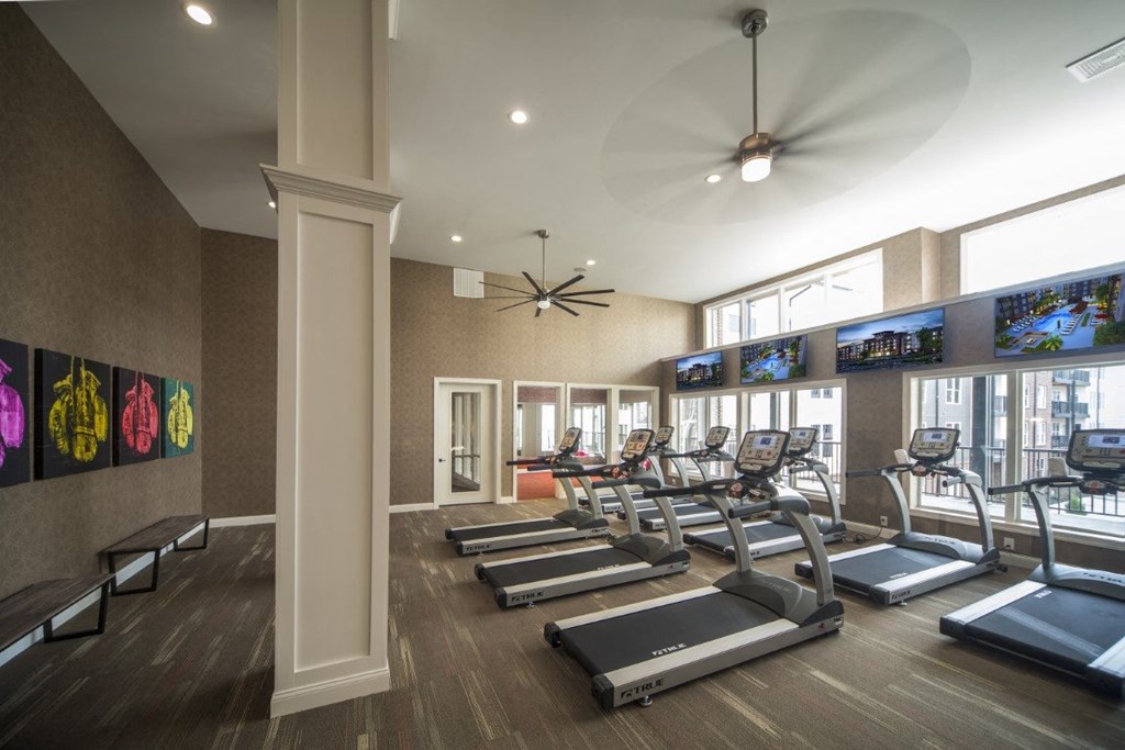 a gym with treadmills and televisions on the wall at Madison Park, Columbus