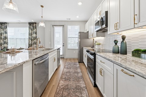 A kitchen with white cabinets and a marble countertop.