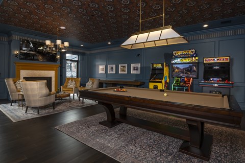 A pool table in a room with a fireplace and a bar.