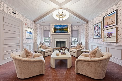 A living room with a fireplace and a painting of a beach scene on the wall.