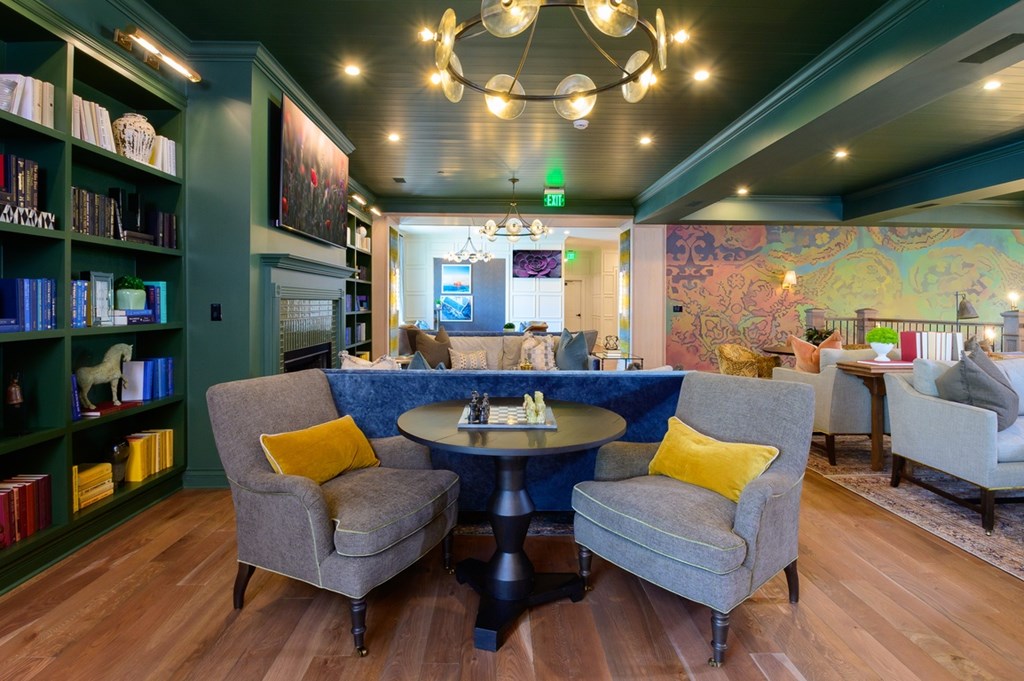 A room with a round table and chairs with yellow pillows.