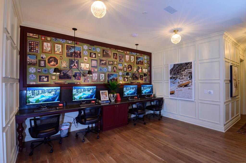 A room with a long wall of computer monitors and a desk with two chairs.