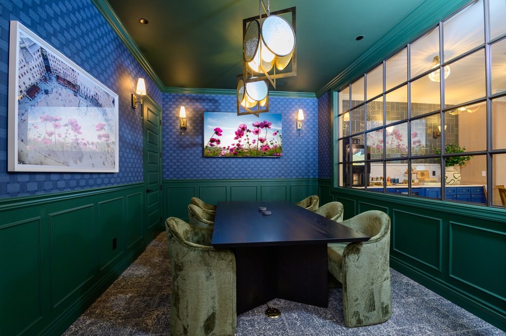 A room with a table and chairs and a painting of a building.
