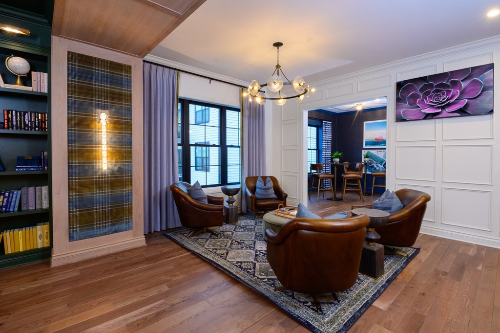 A living room with a chandelier, a couch, a chair, and a rug.