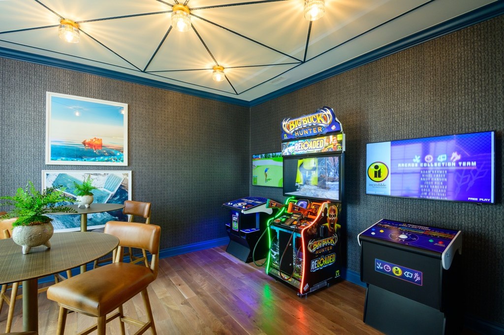 A room with a table, chairs, and a pinball machine.