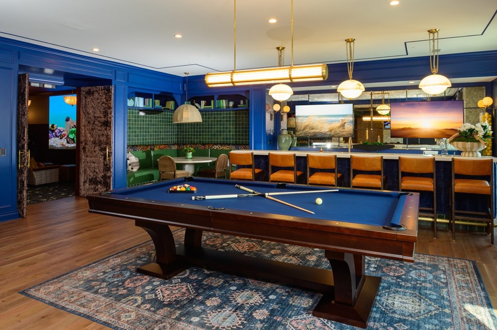 A pool table is in the middle of a room with a blue wall.