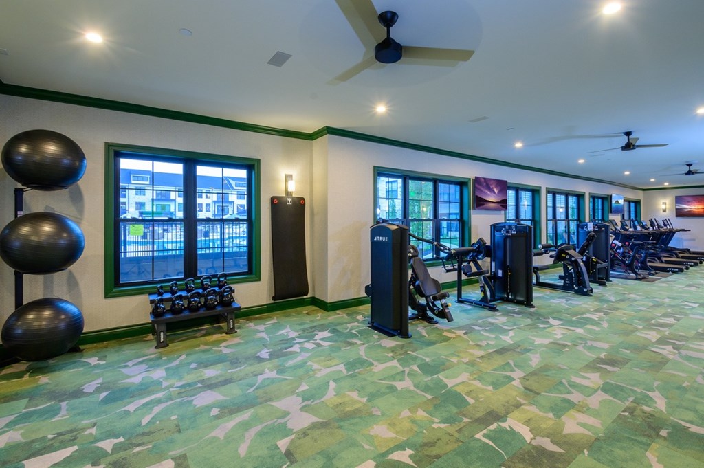 A gym with exercise equipment and a green floor.
