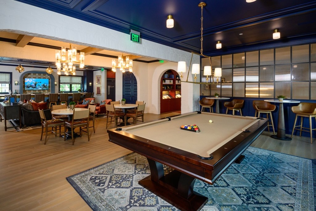 A pool table is in the middle of a room with a blue rug.
