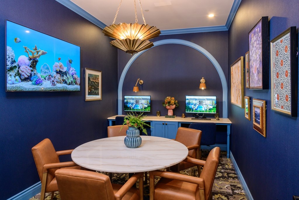 A room with a round table and chairs, a television, and a chandelier.
