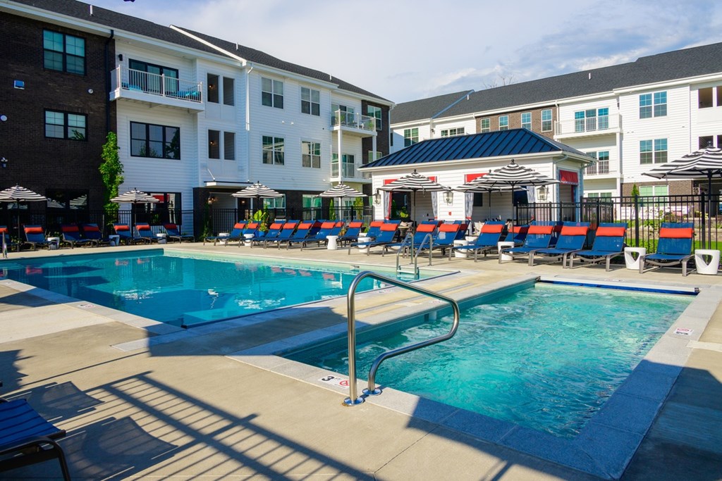 A large swimming pool with a diving board and sun loungers.
