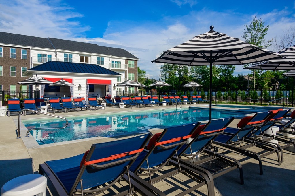 A pool with sun loungers and a building in the background.