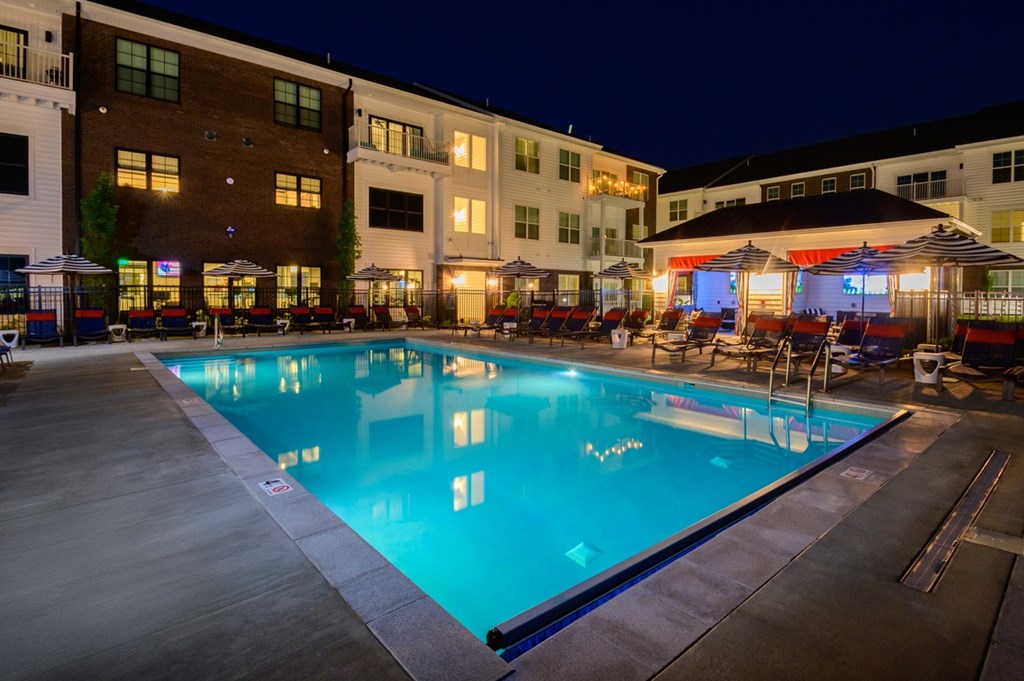 A large swimming pool in front of a building at night.