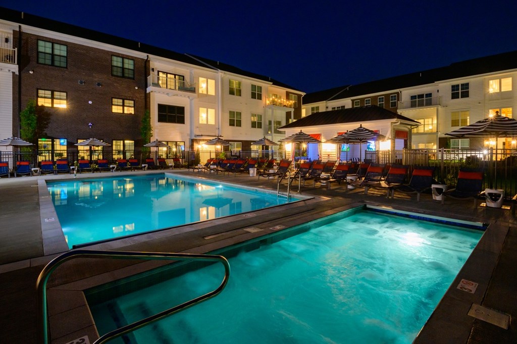 A swimming pool at a resort with a lit patio area.