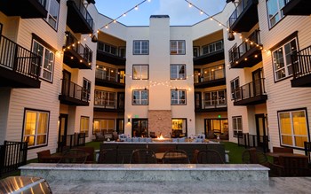 an outdoor patio with a firepit and string lights at the flats at big tex apartments in - Photo Gallery 3
